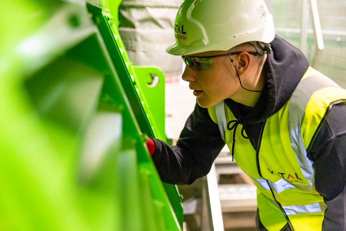 Engineer in high-visibility clothing and hard hat inspecting renewable-energy equipment